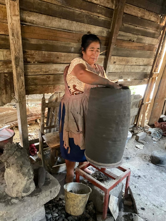 Artisan hand-shaping a large clay vessel in a traditional workshop