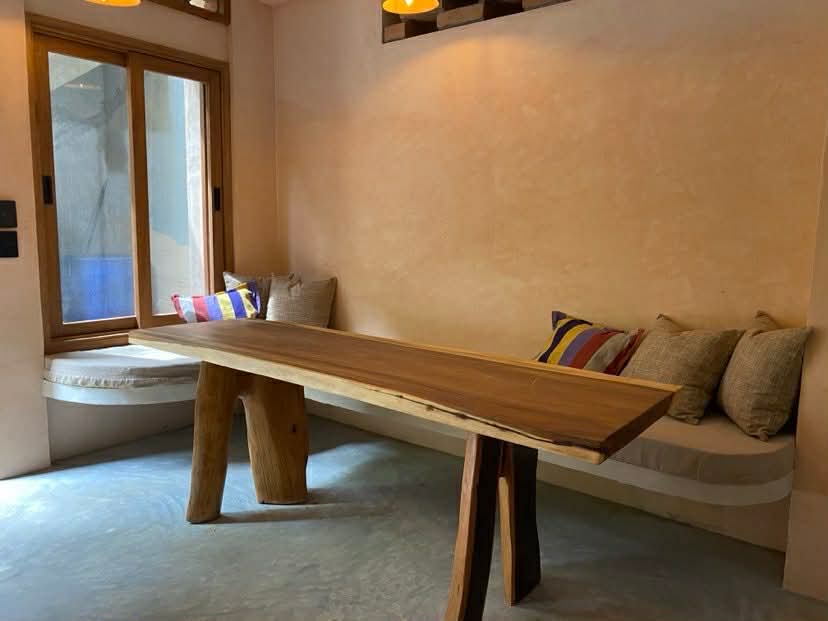 Parota wood dining table with built-in bench, handwoven cushions, and clay lamps