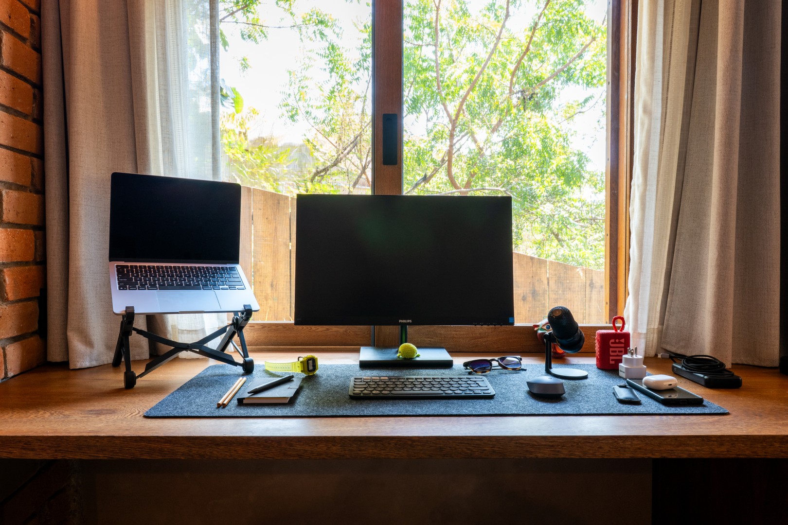 Casa Maradi workspace with parota wood desk, external monitor, laptop stand, and view of the garden
